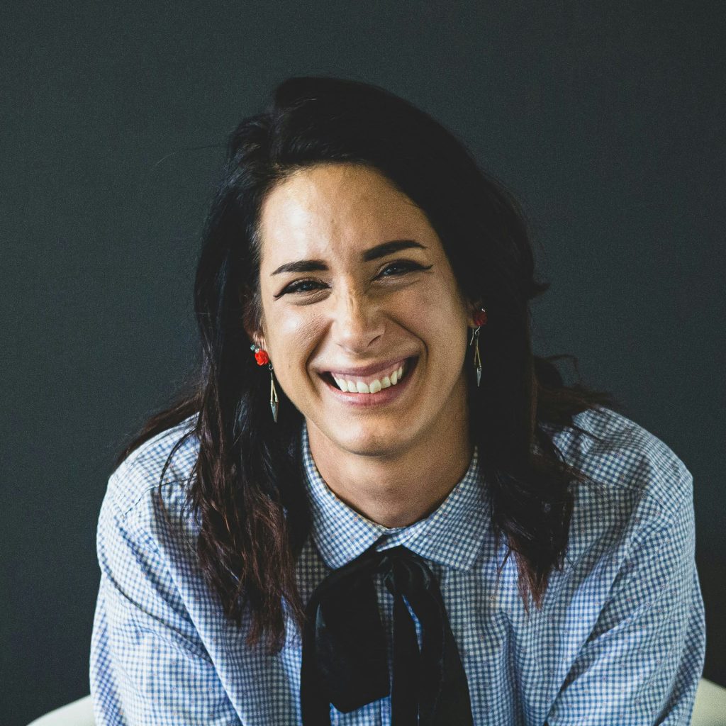 Smiling woman wearing a button down shirt with a bow tie.